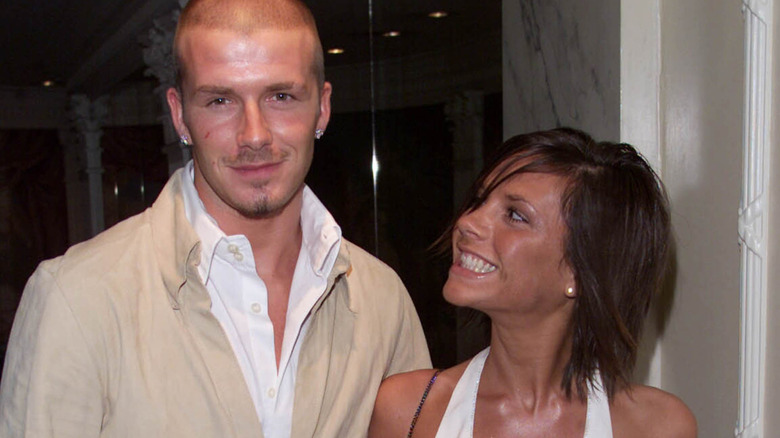 Victoria Beckham smiles at David Beckham as he looks at the camera