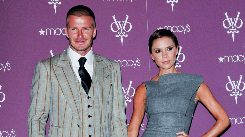 Victoria and David Beckham stand arm-in-arm at a perfume event