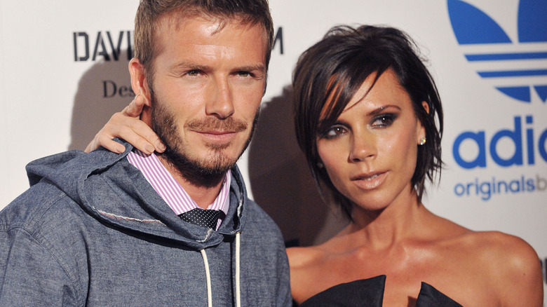 Victoria Beckham places her arm around David Beckham as they pose for a photo