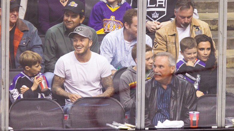 The Beckham family sit in the crowd at a sports match