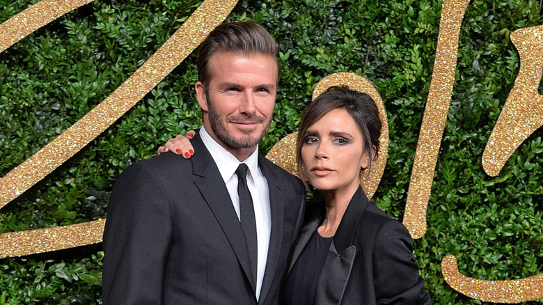 Victoria Beckham places her hand around David Beckham at a red carpet event