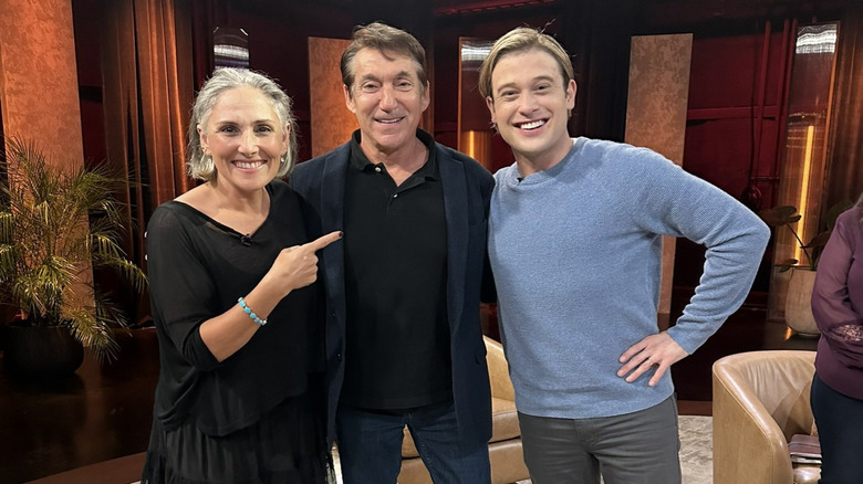 Tyler Henry smiles in a blue sweater backstage with Ricki Lake