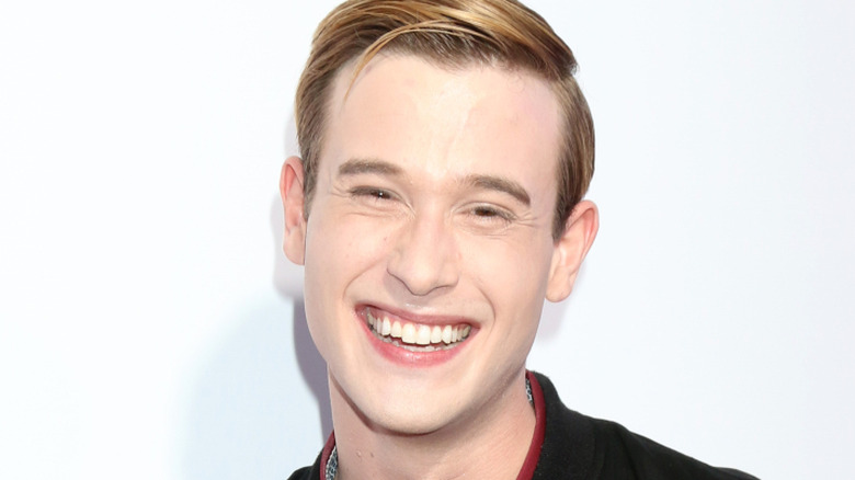 Tyler Henry laughs in front of a white screen