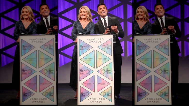 Kelly Ripa and Mark Consuelos talking at a podium in 2018