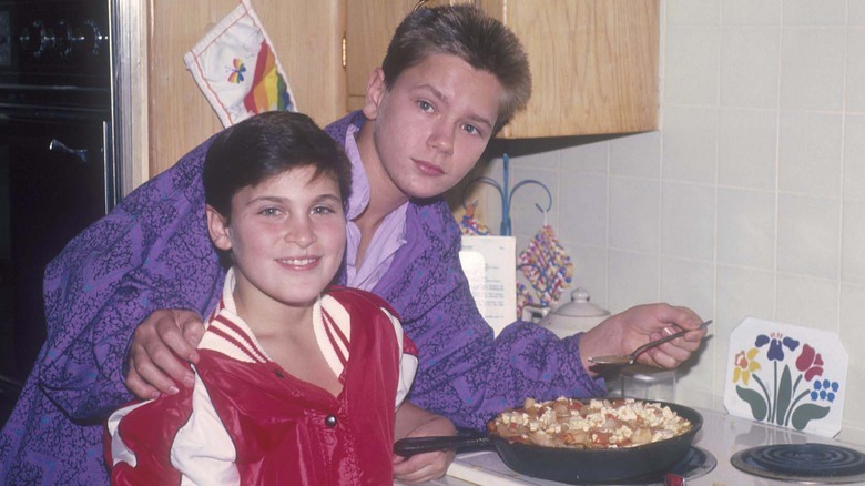 A young River Phoenix and Joaquin Phoenix next to a skillet on a stove