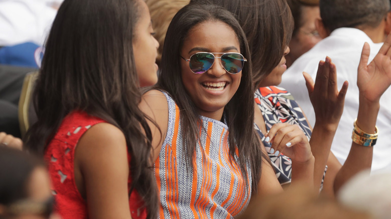 Sasha Obama laughing in sunglasses and a stripy shirt