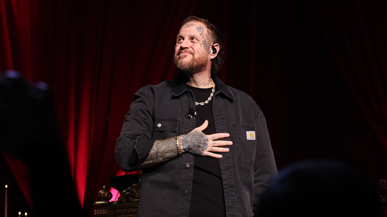 Jelly roll in a black shirt standing with his hand over his heart