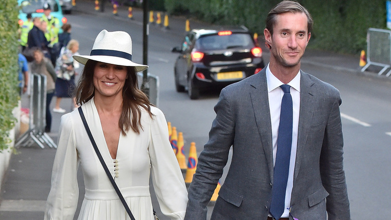 A smiling Pippa Middleton and James Matthews walking hand in hand