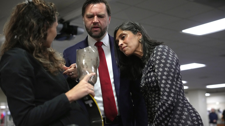 Usha Vance laying her head on husband JD's shoulder while they listen to a woman speal