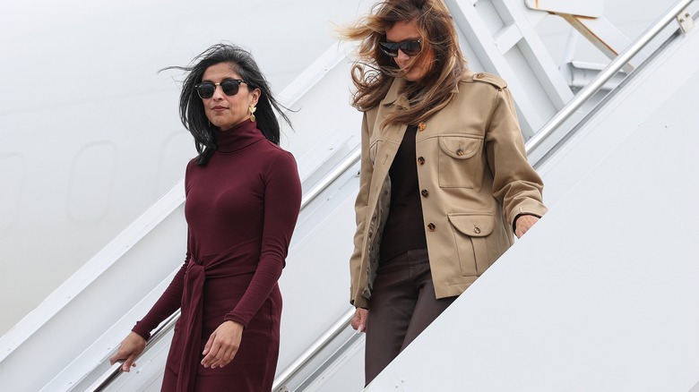 Usha Vance in a maroon dress with Melania Trump descending airplane staircase