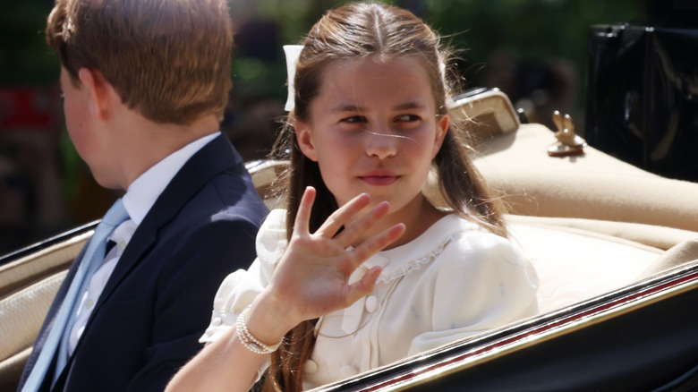 Princess Charlotte waving at onlookers during a carriage ride in a white dress