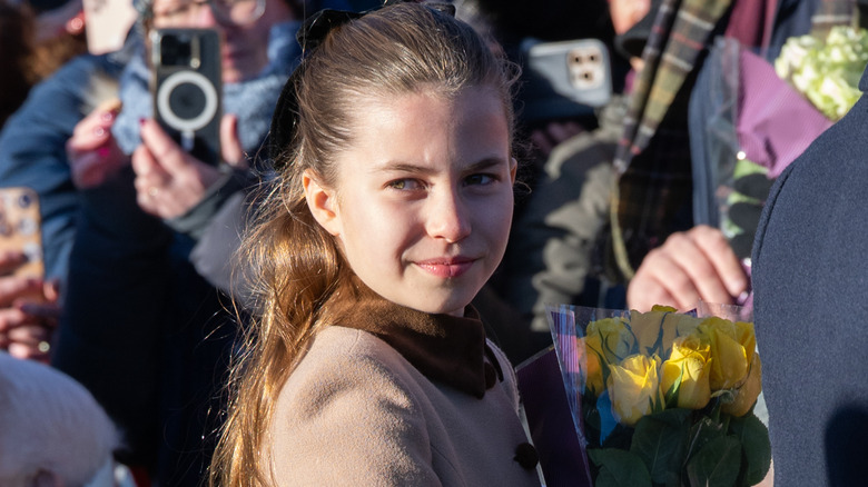 Princess Charlotte smiling at the camera as she accepts gifts from royal fans
