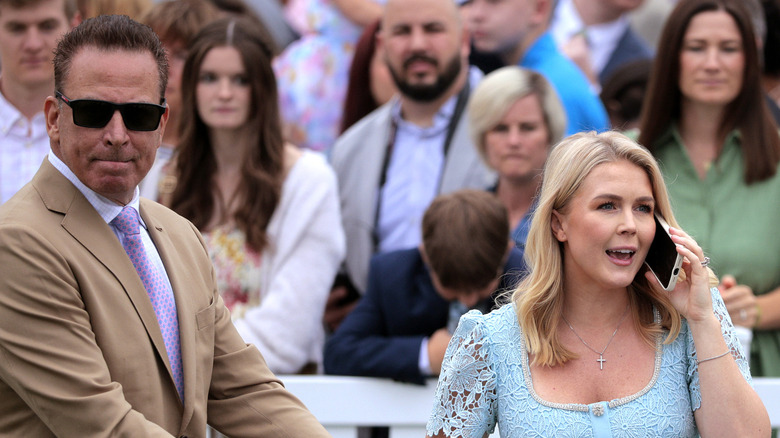 Karoline Leavitt in a blue dress talking on the phone while next to her husband. Nicholas Riccio, who's in a