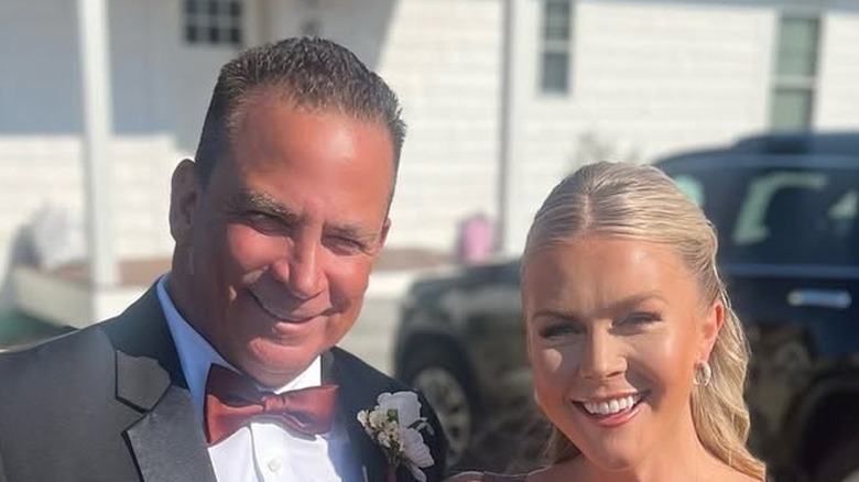 Karoline Leavitt in a brown dress smiling next to Nicholas Riccio at a wedding.