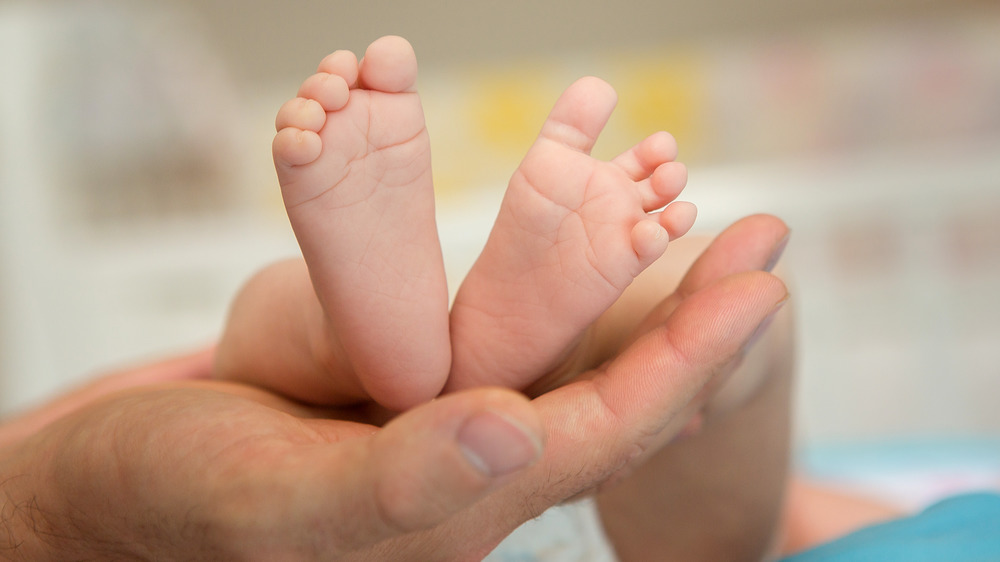 Adult hand holding infant feet