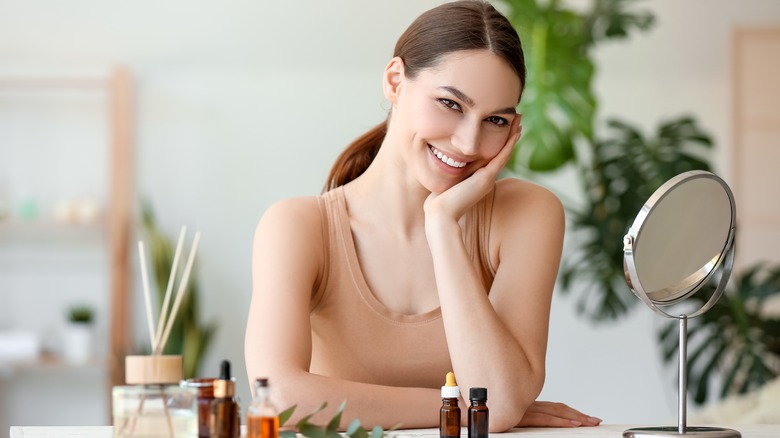 woman smiling while surrounded by bottles of oil