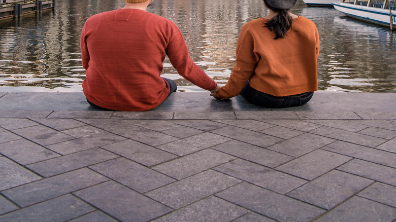 couple sitting in front of a canal in Amsterdam