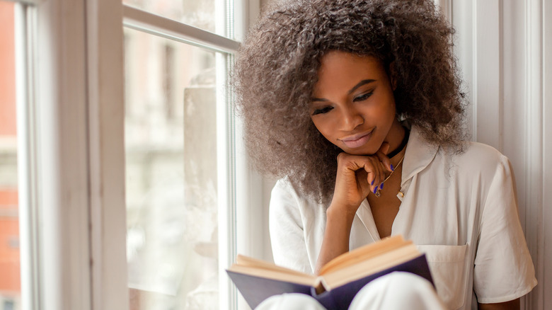 woman reading a book in a window