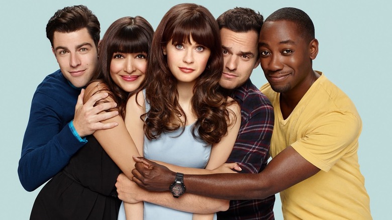 The cast of New Girl hugging and smiling for a promotional photo.