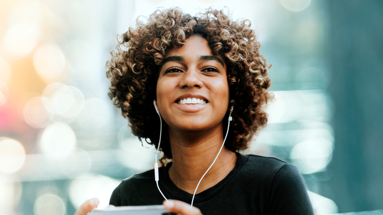 Curly-haired woman listening to earphones 