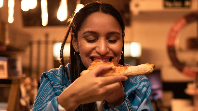 woman happily eating pizza slice
