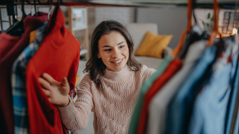 Woman looking through clothes in closet 