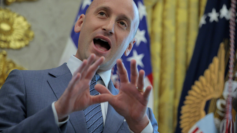 Stephen Miller talking with his hands in a grey suit