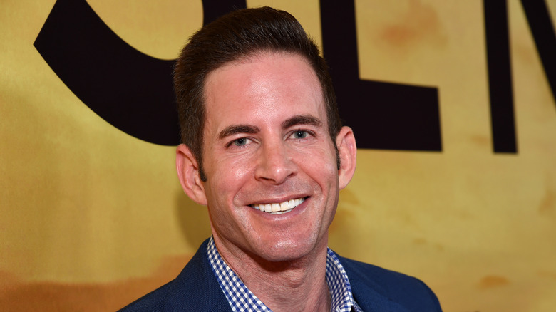 Tarek El Moussa smiling in a blue jacket and check blue and white shirt at an event