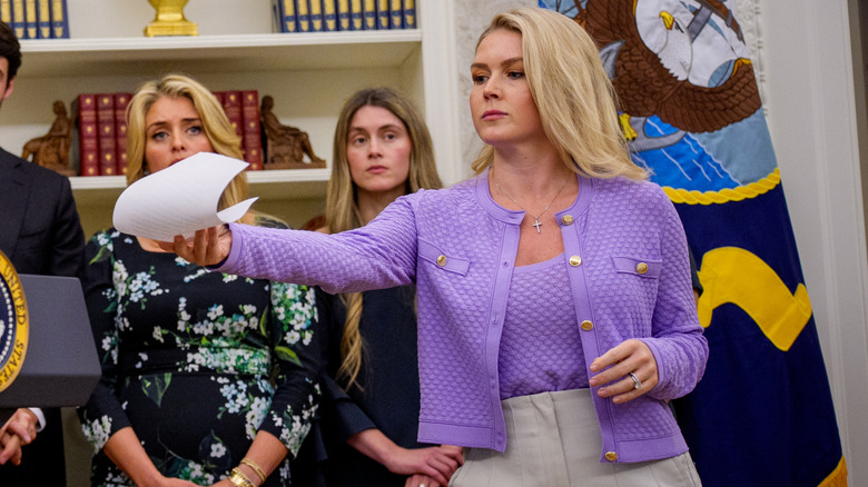 Karoline Leavitt handing a paper to Donald Trump