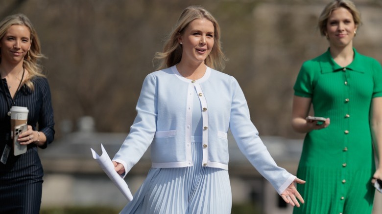 Karoline Leavitt walks up to a group of reporters outside the West Wing of the White House (2025)
