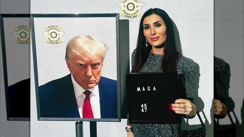 Laura Loomer posing next to Donald Trump's mugshot