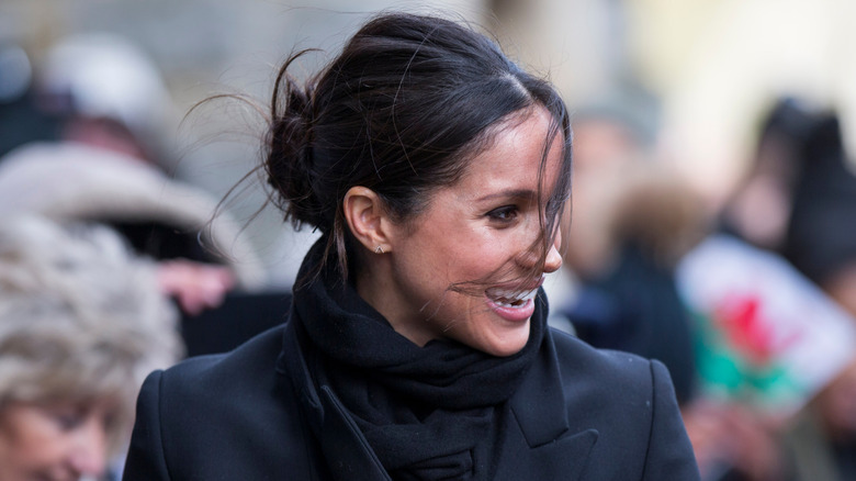 Meghan Markle laughing as she observes something
