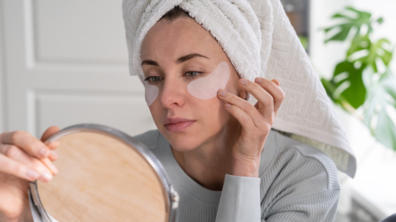 woman analyzing face in mirror