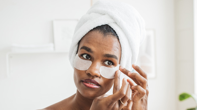 Woman applies eye masks to face