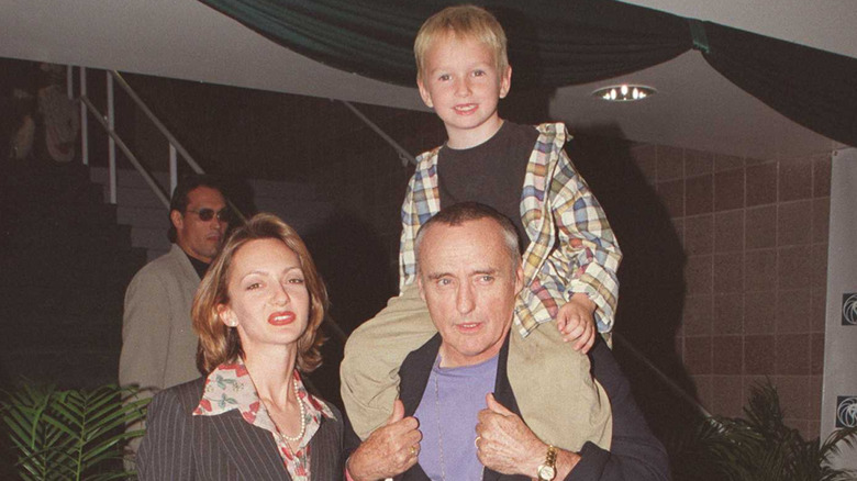Dennis Hopper posing next to his wife while carrying his smiling son on his shoulders