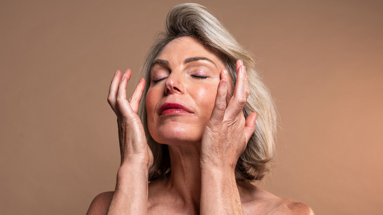 Older woman applying oil to face
