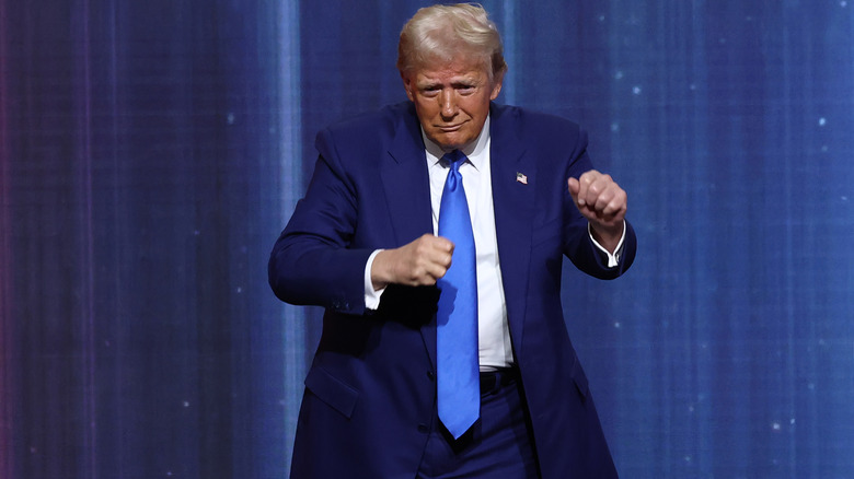 Donald Trump doing a dance in front of blue curtains