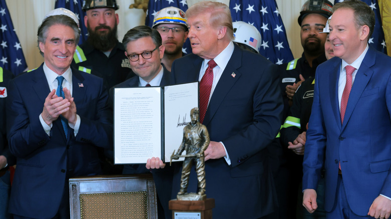 Donald Trump posing with an executive order and his Undisputed Champion of Beautiful, Clean Coal trophy