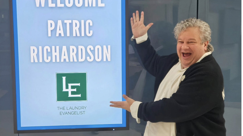 Patric Richardson posing next to a sign at an event