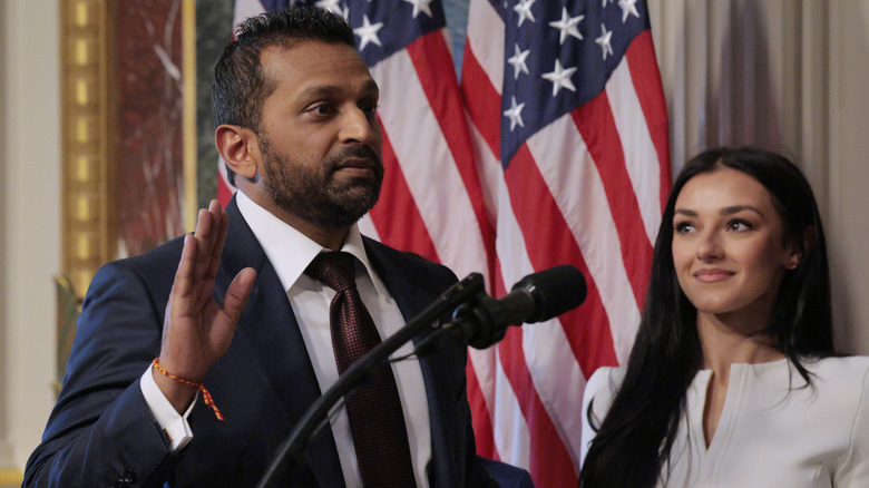 Kash Patel being sworn in with his hand raised and Alexis Wilkins beside him.