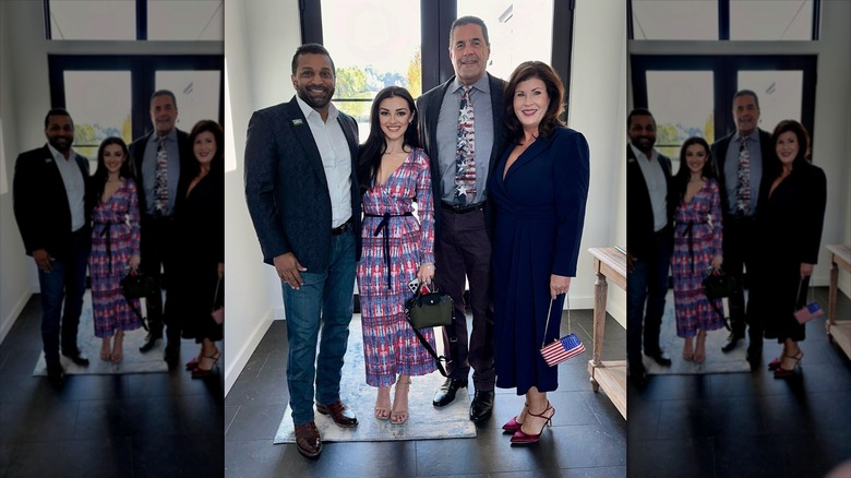 Kash Patel with Alexis Wilkins and her parents inside a brightly lit room.