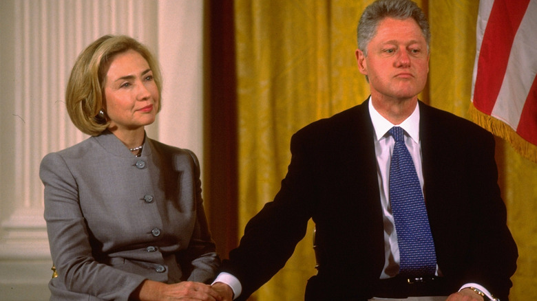 Bill Clinton with his hand on Hillary Clinton's knee