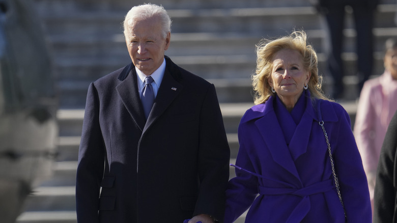 Jill Biden and Joe Biden holding hands as they walk together outside