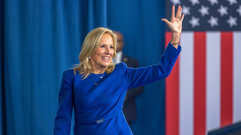 Jill Biden waving on stage against American flag