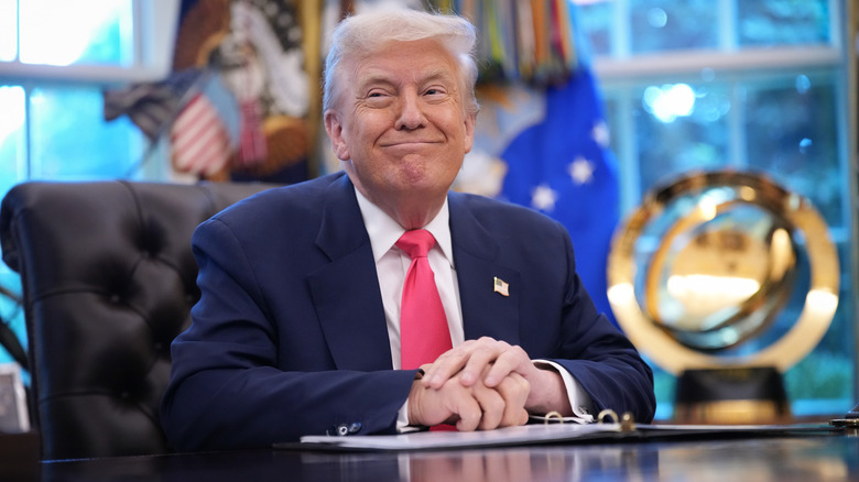 Donald Trump grinning from behind the Resolute Desk