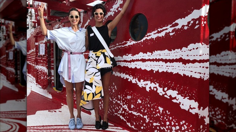 Elena Moussa with friend, posing among red mural art.
