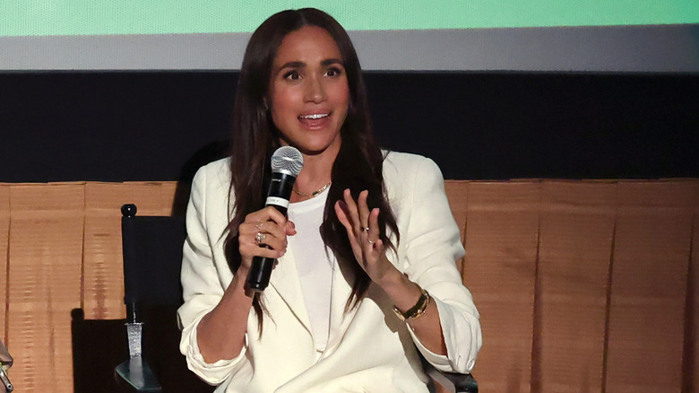 Meghan Markle sitting in director's chair speaking into microphone