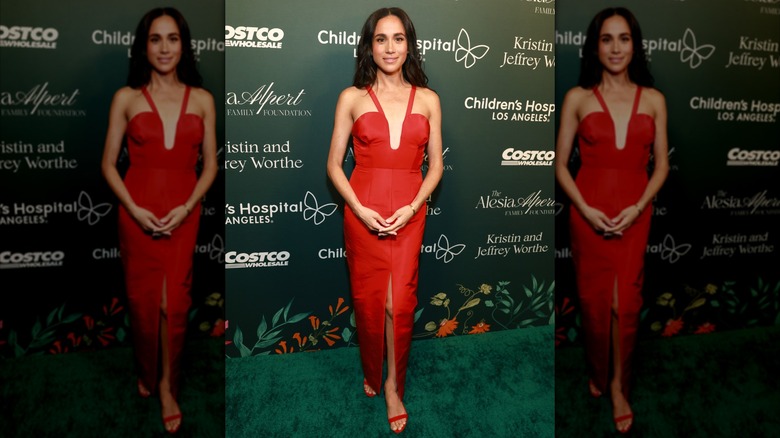 Meghan Markle posing on the red carpet in a cleavage baring tight red dress