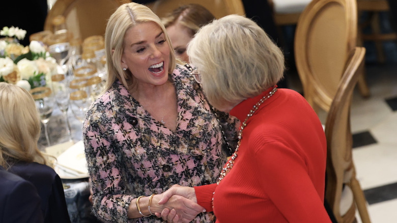 Pam Bondi in a dining area with a woman in red.