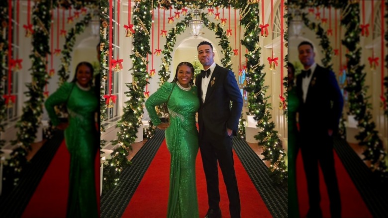 Under a Christmas arch of green garland and red ribbon stands congresswoman Cori Bush and Courtney Merritt.